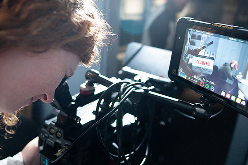 A student looking into a film camera.