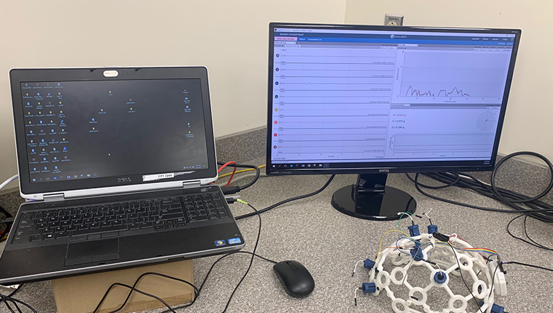 A computer sitting on a desk with lab equipment surrounding it.