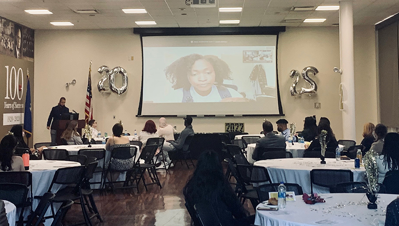 Ivy Watts ’15 (on screen) delivers the keynote address.