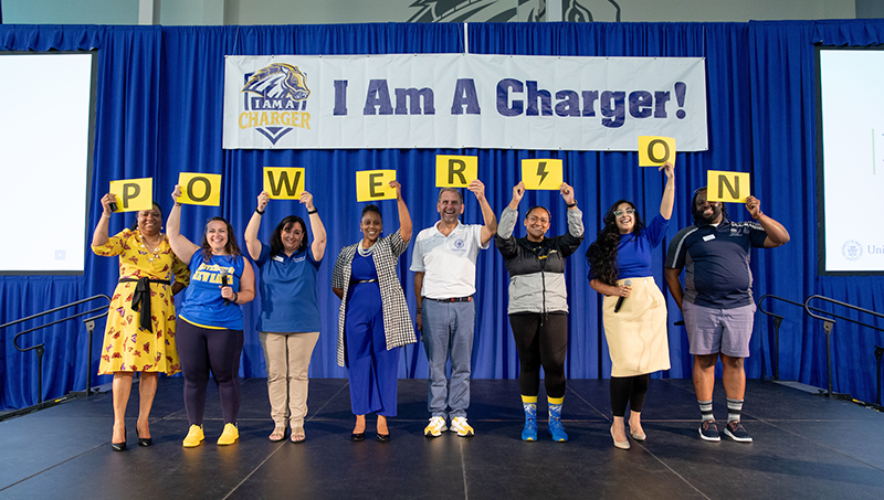 Staff pose for a photo on stage.