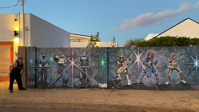 Josh Carbajal ’18, ’20 M.A. in front of a mural depicting two of his favorite bands in Phoenix, AZ.