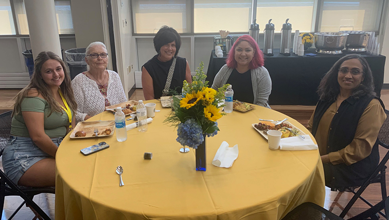 A group of people gather around a table.