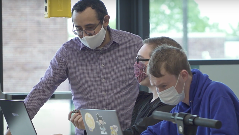 Christopher Martinez, Ph.D. (left), and students at a desk working.