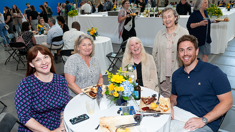 Smiling people gathered around a table, posing for a photo.