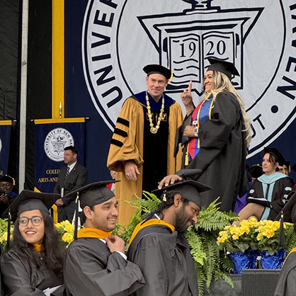 Martine Bernadel ’24 M.S. on stage with University President Jens Frederiksen, Ph.D.